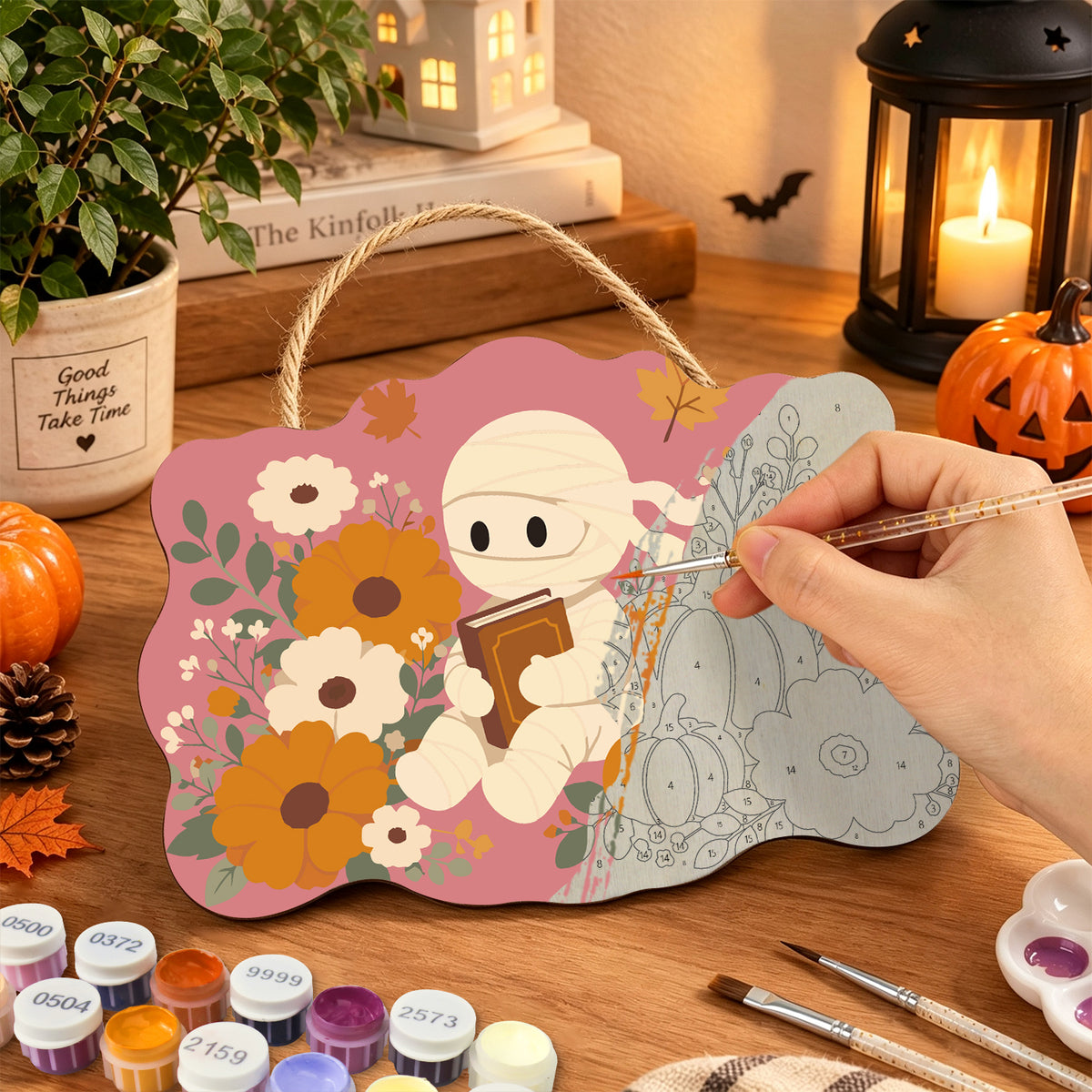 Pancarte Momie au Jardin Rose en cours de peinture, pinceau à la main — Maison Artsen